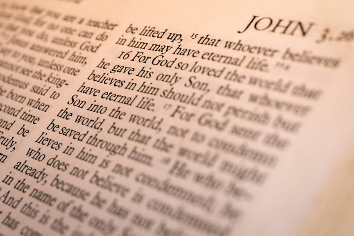 Close-up of a Bible page focusing on the John section, with visible verse text and the word 'JOHN'.