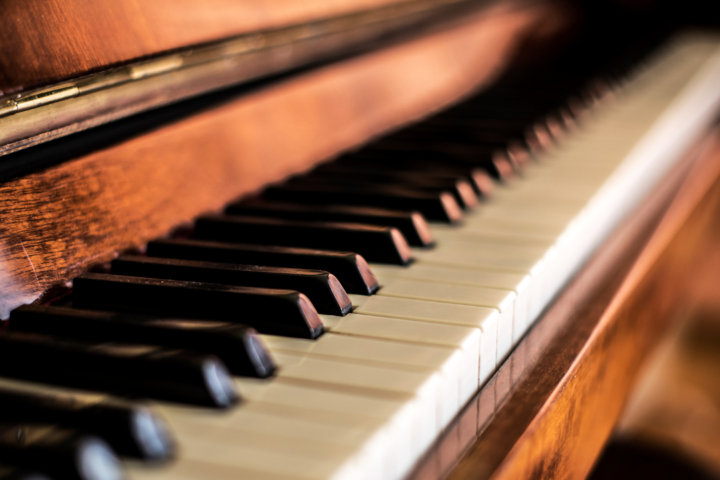 Close-up of a wooden piano keyboard and keys, highlighting the instrument's rich, warm finish and texture.